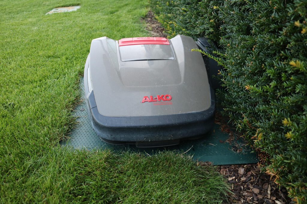 Ein Mähroboter im Garten an der Hecke
